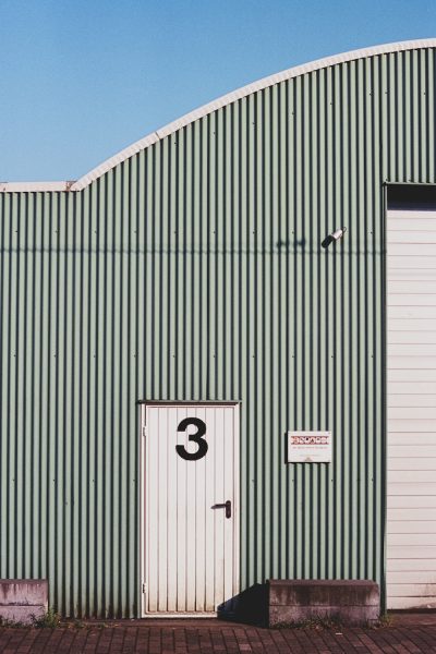 A newly built light green steel warehouse with a white roof for a manufacturing company 